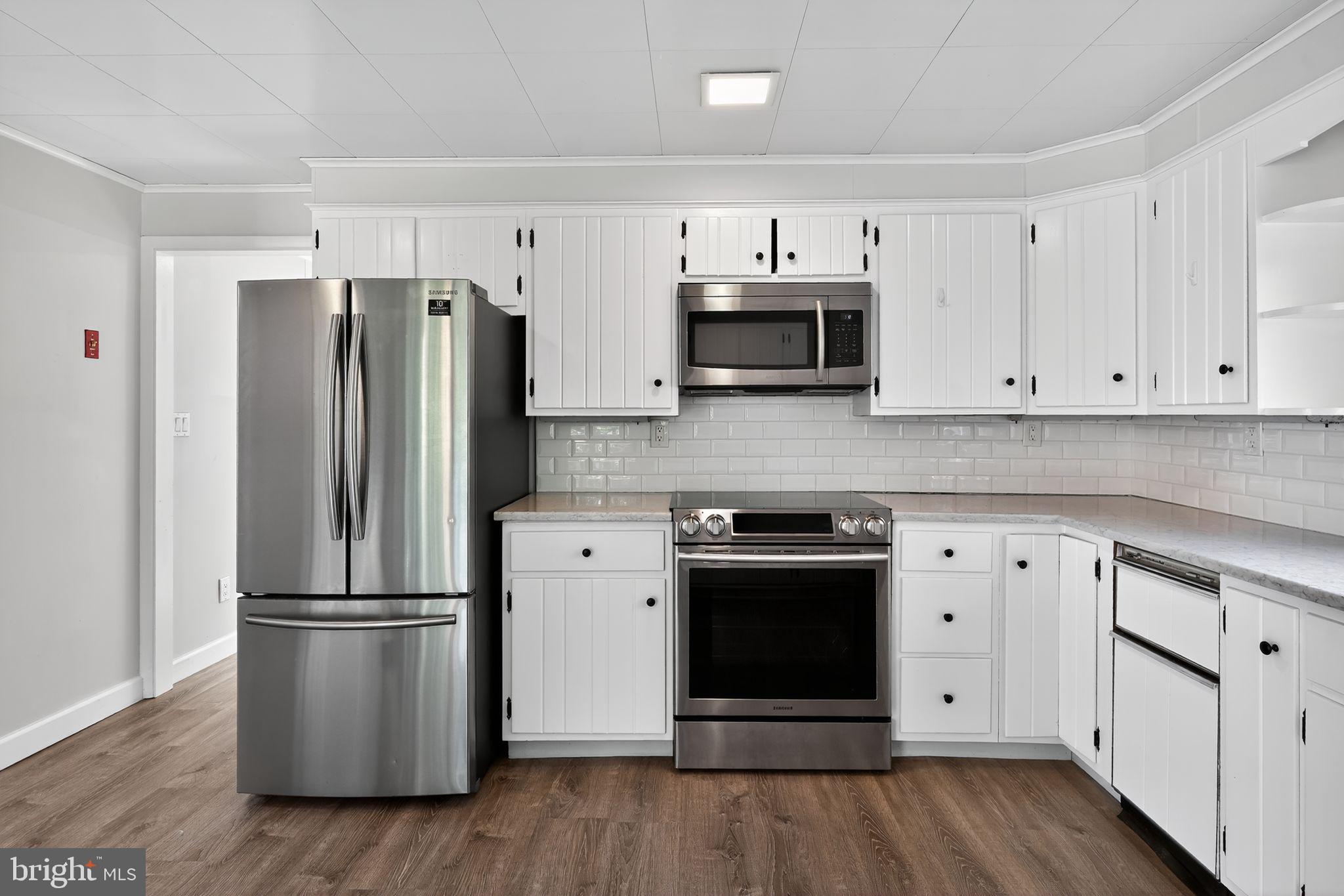 7523 B Street Chesapeake Beach, MD 20732 - Photo 4 of 29 a kitchen with stainless steel appliances white cabinets white stove a microwave and a refrigerator