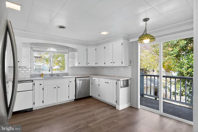 a kitchen with granite countertop a stove a sink and white cabinets with wooden floor
