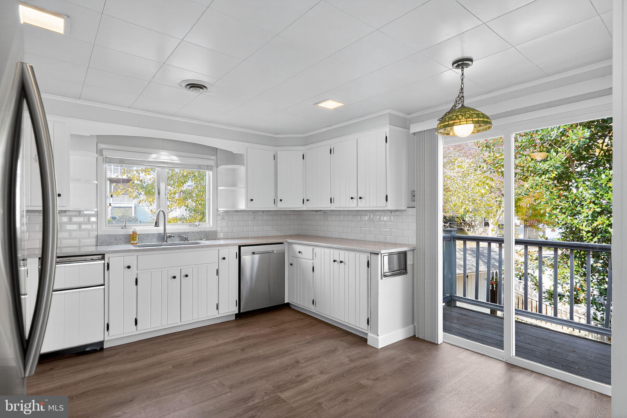 7523 B Street Chesapeake Beach, MD 20732 - Photo 5 of 29 a kitchen with granite countertop a stove a sink and white cabinets with wooden floor