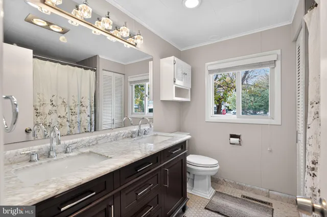 a bathroom with a granite countertop sink a large mirror a toilet and a window