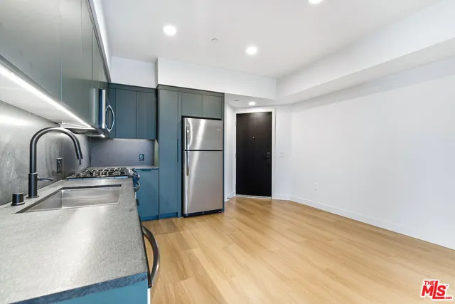 a kitchen with stainless steel appliances granite countertop a refrigerator a sink and a stove