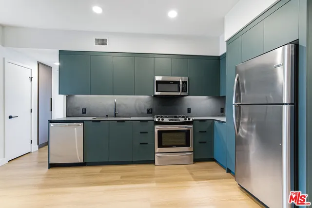 a kitchen with stainless steel appliances granite countertop a refrigerator and a stove top oven