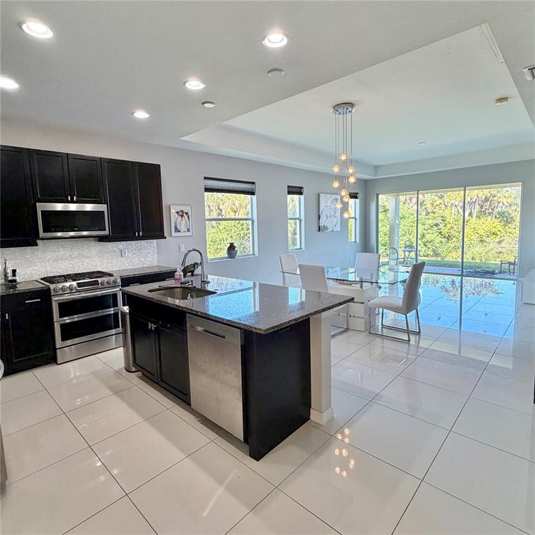 3105 Trustee Avenue Sarasota, FL 34243 - Photo 3 of 14 a kitchen with stainless steel appliances a stove a sink a microwave a dining table and chairs