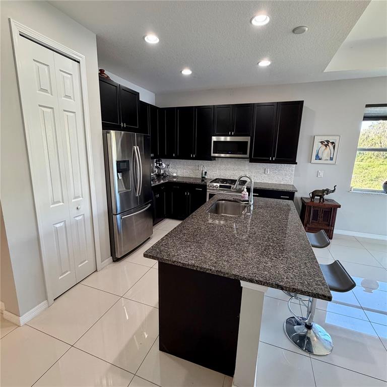 3105 Trustee Avenue Sarasota, FL 34243 - Photo 4 of 14 a kitchen with stainless steel appliances kitchen island granite countertop a refrigerator a sink a stove with wooden cabinets
