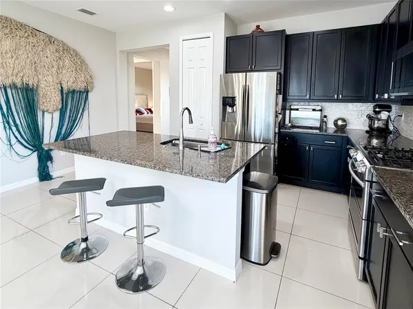 a kitchen with stainless steel appliances granite countertop a refrigerator a stove and a sink