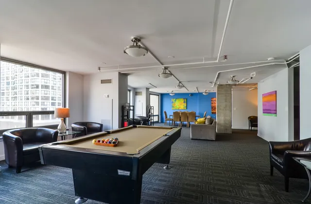 a living room with furniture pool table wooden floor and windows