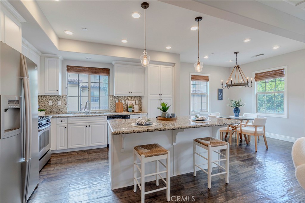 140 Full Moon Irvine, CA 92618 - Photo 11 of 38 a kitchen with a dining table chairs wooden floor cabinets appliances and a window
