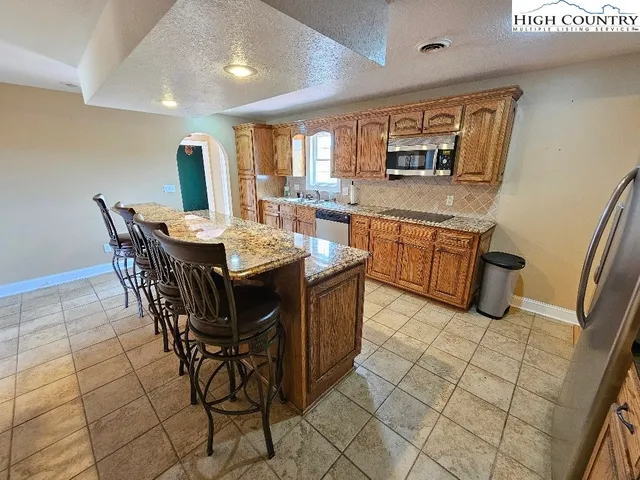 a dining hall with stainless steel appliances granite countertop a stove a sink a dining table and chairs
