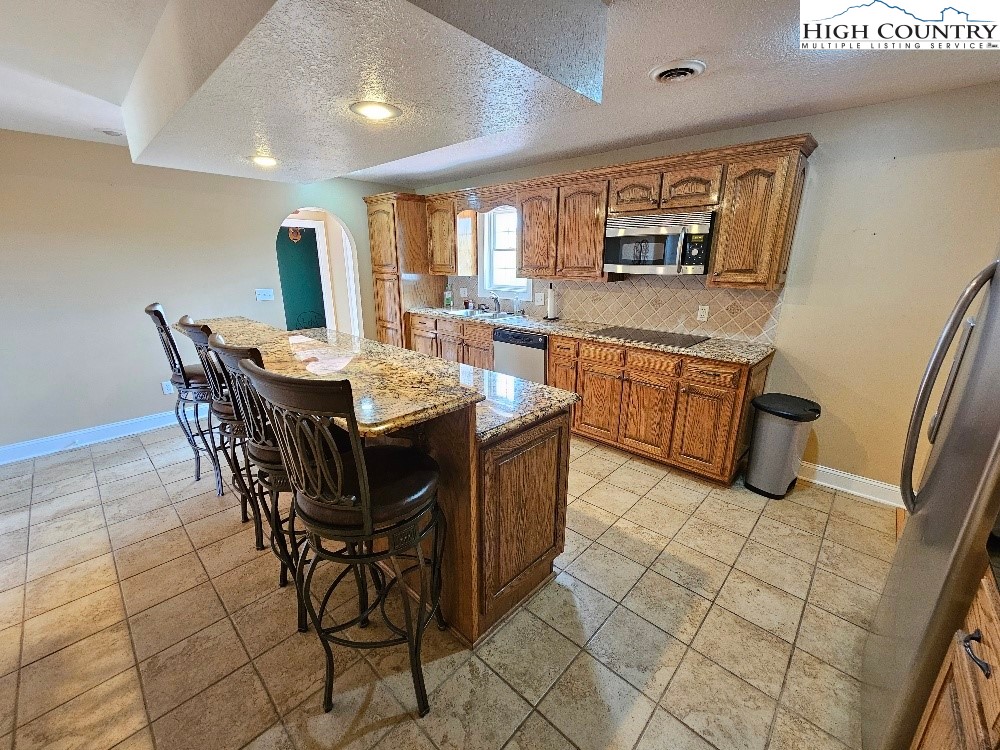 611 Barrett Road Ennice, NC 28623 - Photo 22 of 45 a dining hall with stainless steel appliances granite countertop a stove a sink a dining table and chairs