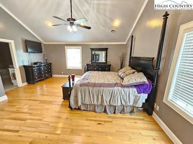 a spacious bedroom with a bed a window and a flat screen television