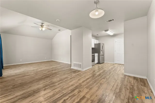 a view of empty room with wooden floor and windows