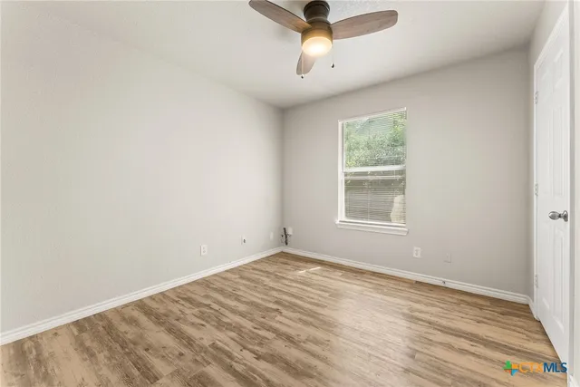 an empty room with a window and a ceiling fan