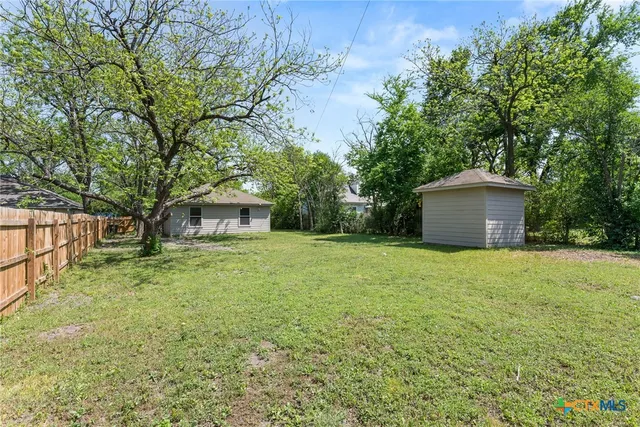 a backyard of a house with large trees and plants