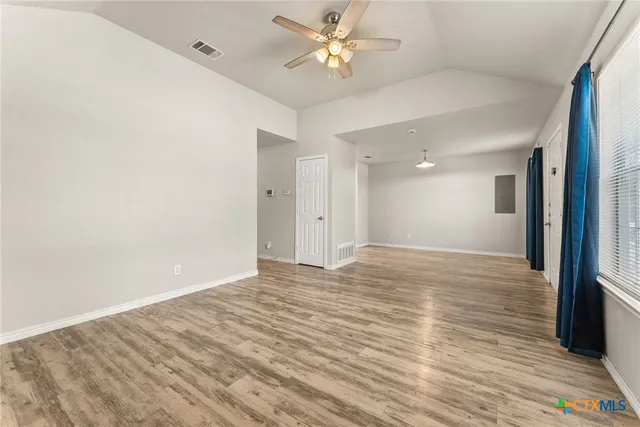 a view of empty room with wooden floor and fan