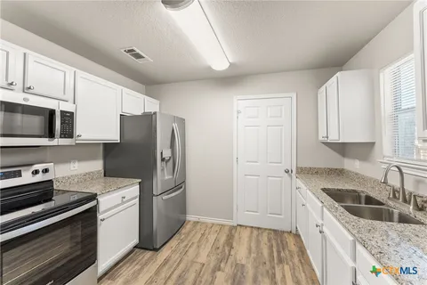 a kitchen with granite countertop a refrigerator stove and sink