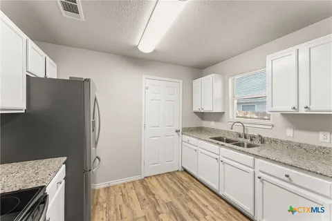 a kitchen with a sink a refrigerator and cabinets