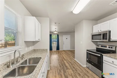 a kitchen with granite countertop a sink wooden floor and stainless steel appliances
