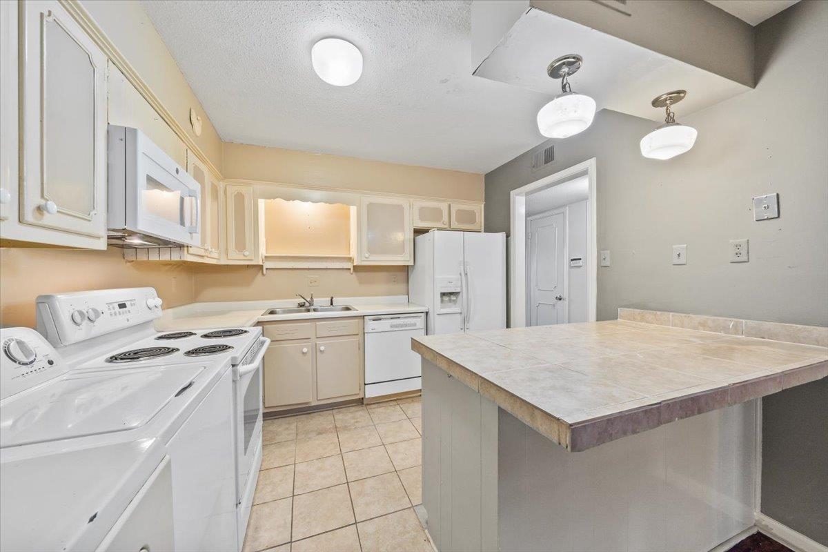 875 South Yates Road, Unit 4 Memphis, TN 38120 - Photo 15 of 25 Kitchen with white appliances, separate washer and dryer, light tile patterned floors, a textured ceiling, and glass insert cabinets
