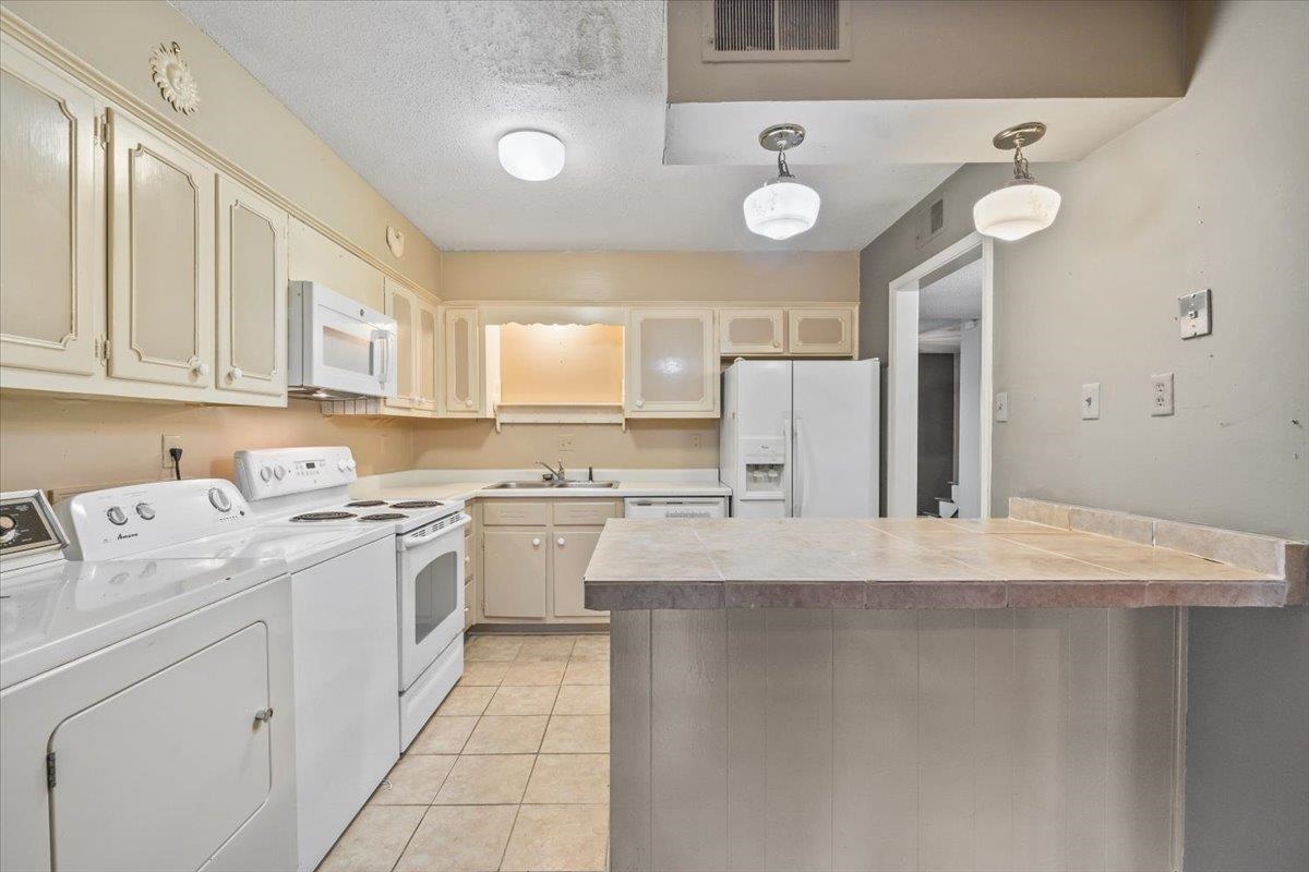 875 South Yates Road, Unit 4 Memphis, TN 38120 - Photo 16 of 25 Kitchen with white appliances, washer and clothes dryer, light tile patterned floors, pendant lighting, and a textured ceiling