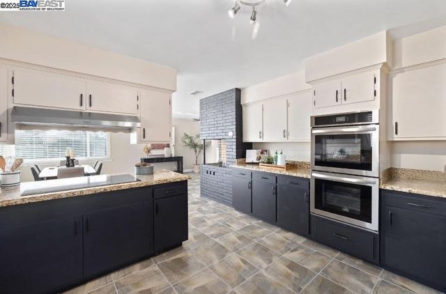 a kitchen with kitchen island granite countertop a sink cabinets and stainless steel appliances