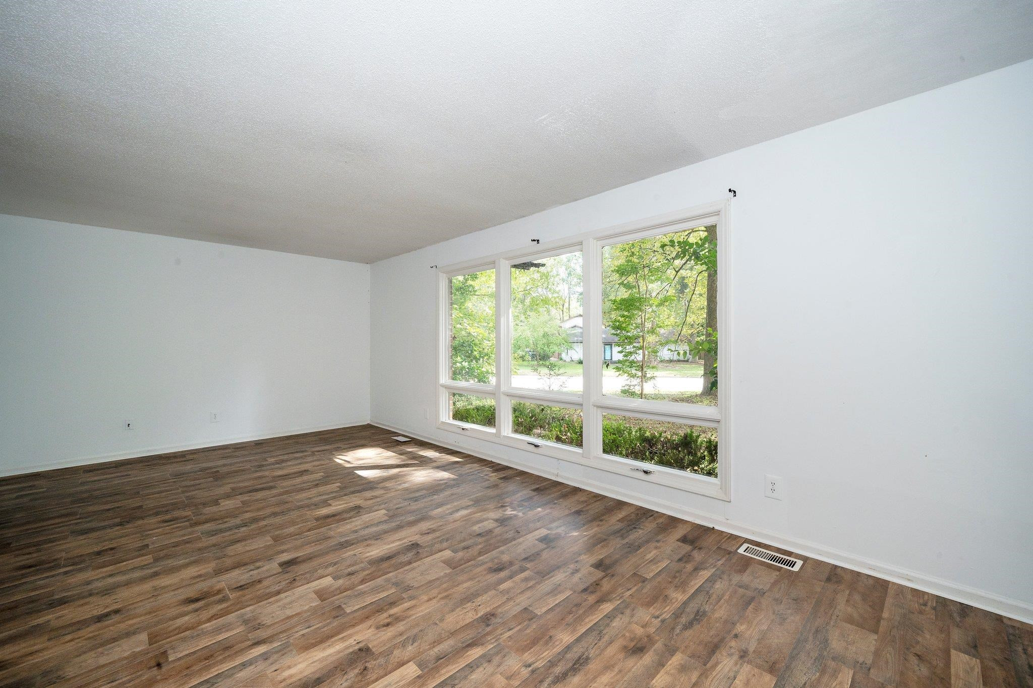 1307 Brookgreen Drive Cary, NC 27511 - Photo 13 of 26 a view of an empty room with wooden floor and a window