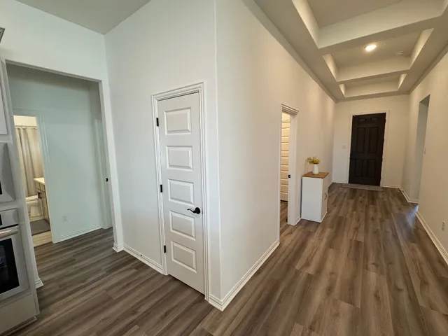 a view of a hallway with wooden floor and a bathroom
