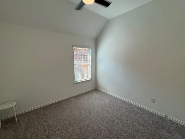 an empty room with windows and chandelier fan