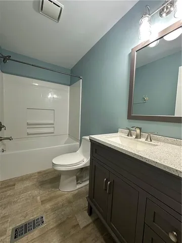 a bathroom with a granite countertop sink toilet a mirror and bathtub