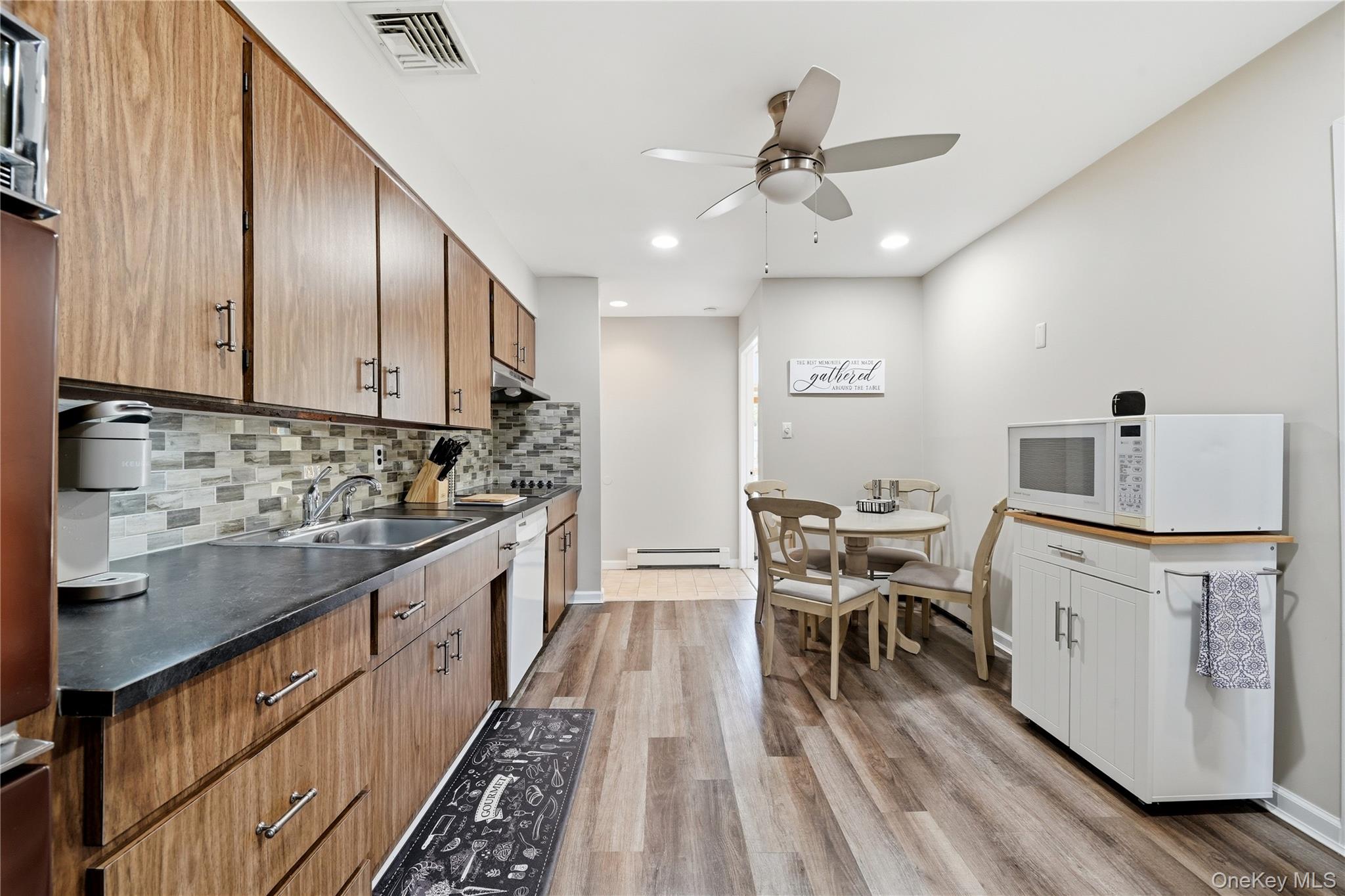 1853 Decatur Avenue Merrick, NY 11566 - Photo 15 of 43 a kitchen with stainless steel appliances kitchen island granite countertop a stove top oven a sink a dining table and chairs with wooden floor