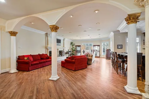 a kitchen with stainless steel appliances granite countertop a stove top oven a sink a dining table and chairs with wooden floor