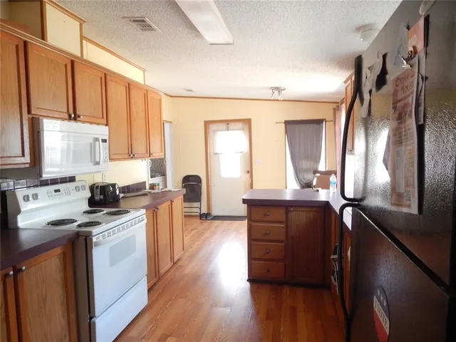 a kitchen with stainless steel appliances kitchen island granite countertop a stove a sink dishwasher and a refrigerator with wooden floor