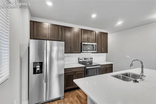 a kitchen with stainless steel appliances granite countertop a refrigerator a sink a stove and oven