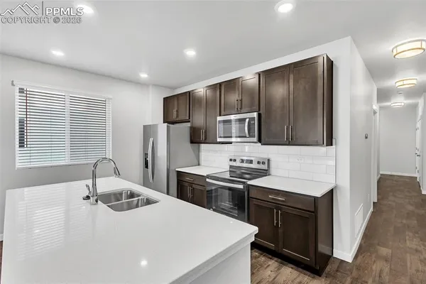 a kitchen with stainless steel appliances kitchen island granite countertop a sink stove and refrigerator