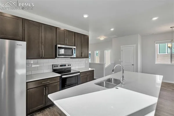 a kitchen with stainless steel appliances a stove a sink a microwave a refrigerator and cabinets