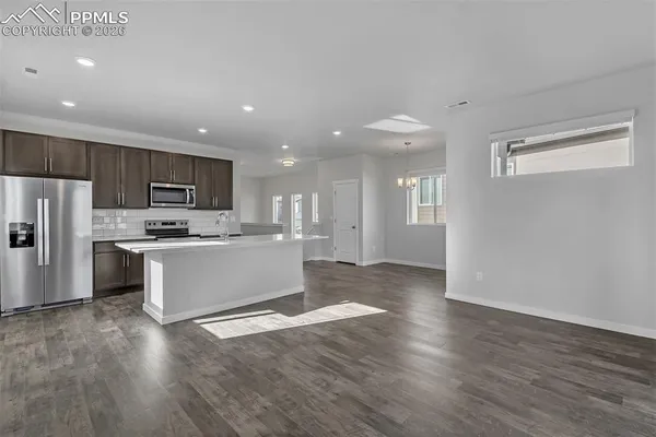 a large kitchen with kitchen island a sink dishwasher a refrigerator and a stove with wooden floor