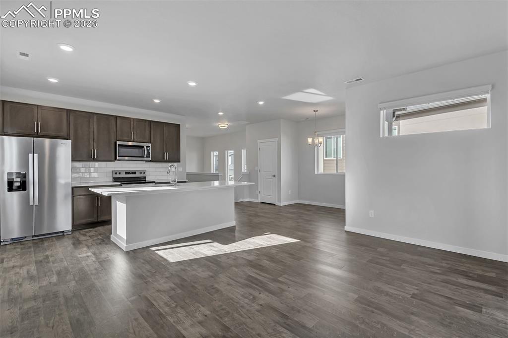 13633 Flurry Heights Colorado Springs, CO 80921 - Photo 8 of 31 a large kitchen with kitchen island a sink dishwasher a refrigerator and a stove with wooden floor