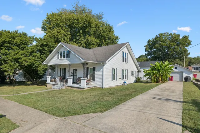 a front view of a house with garden and trees
