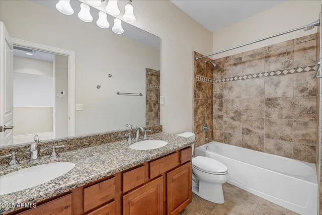 a bathroom with a granite countertop sink a toilet a mirror a bathtub and shower