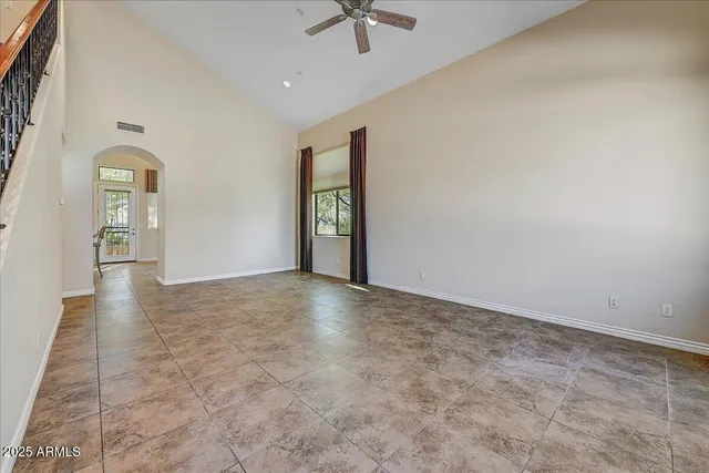 an empty room with chandelier fan and windows