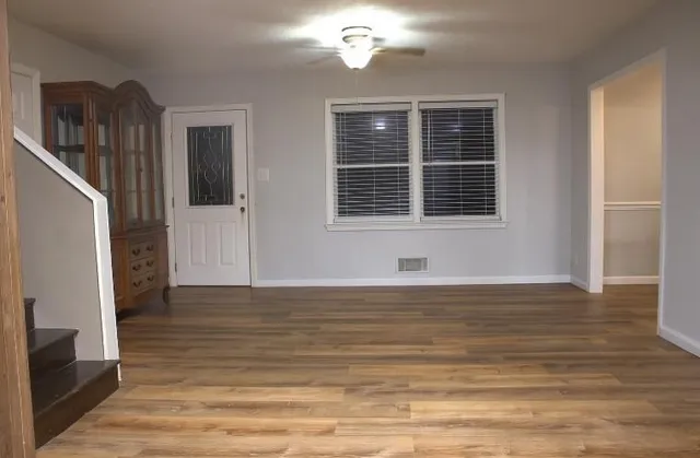 a view of an empty room with wooden floor and a window