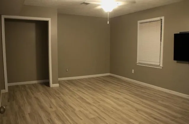 an empty room with wooden floor and windows