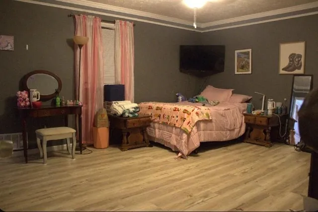 a bedroom with a bed table and a flat screen tv