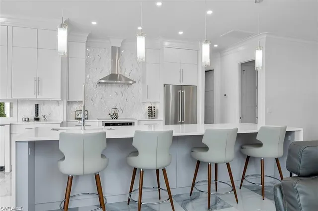 a kitchen with stainless steel appliances kitchen island granite countertop a dining table chairs and white cabinets