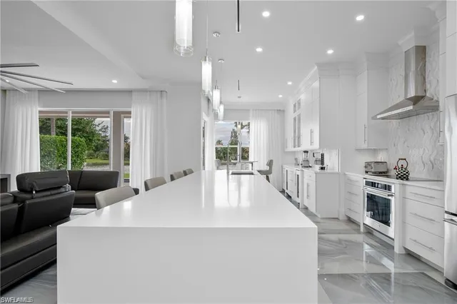 a large white kitchen with a large window and stainless steel appliances