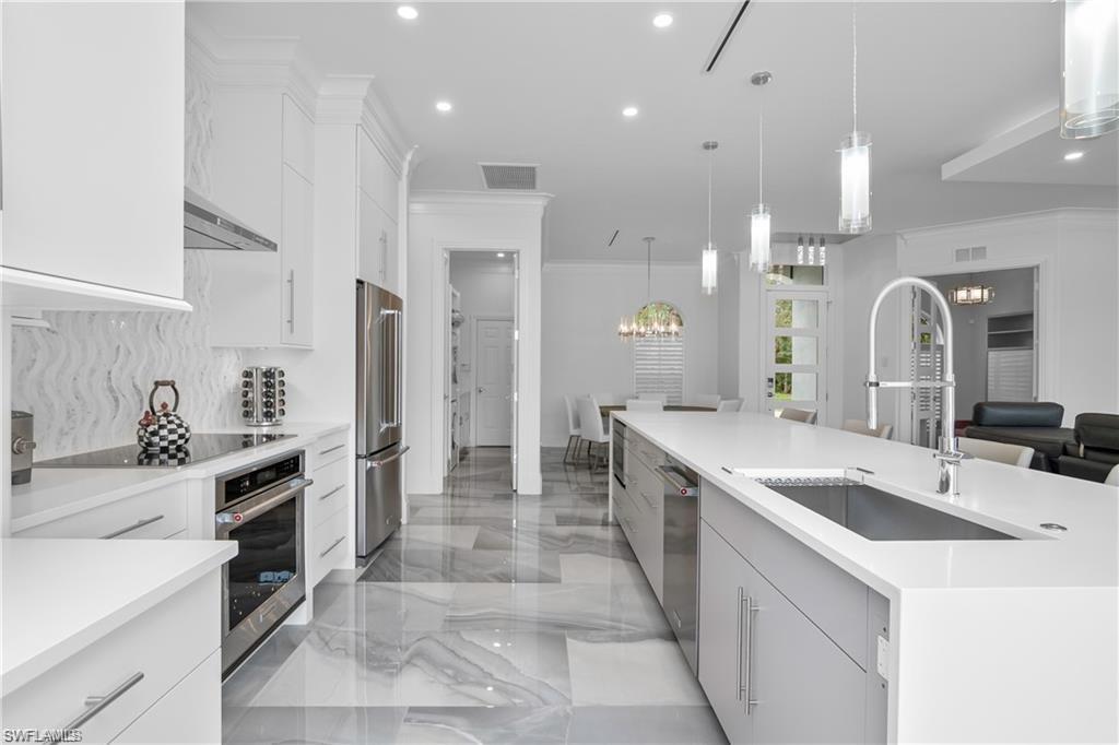 8967 Lely Island Circle Naples, FL 34113 - Photo 19 of 46 a large kitchen with a sink and cabinets