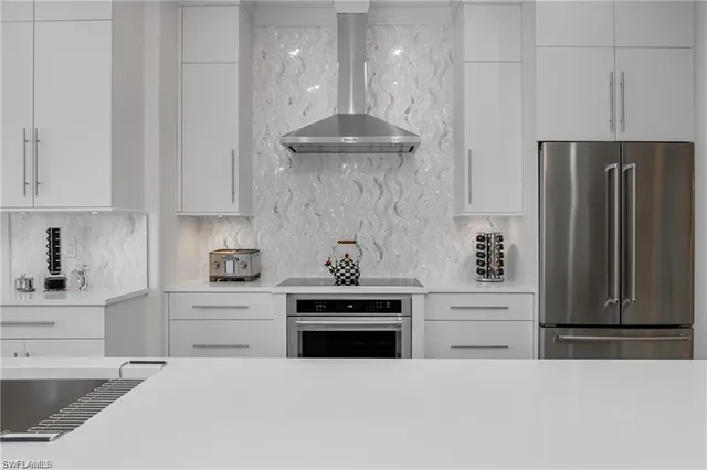 a kitchen with stainless steel appliances granite countertop a stove a refrigerator and a white cabinets