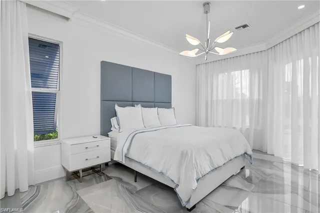 a bedroom with a large bed chandelier and a window