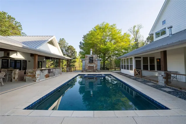 a swimming pool with patio outdoor seating and yard in front of it