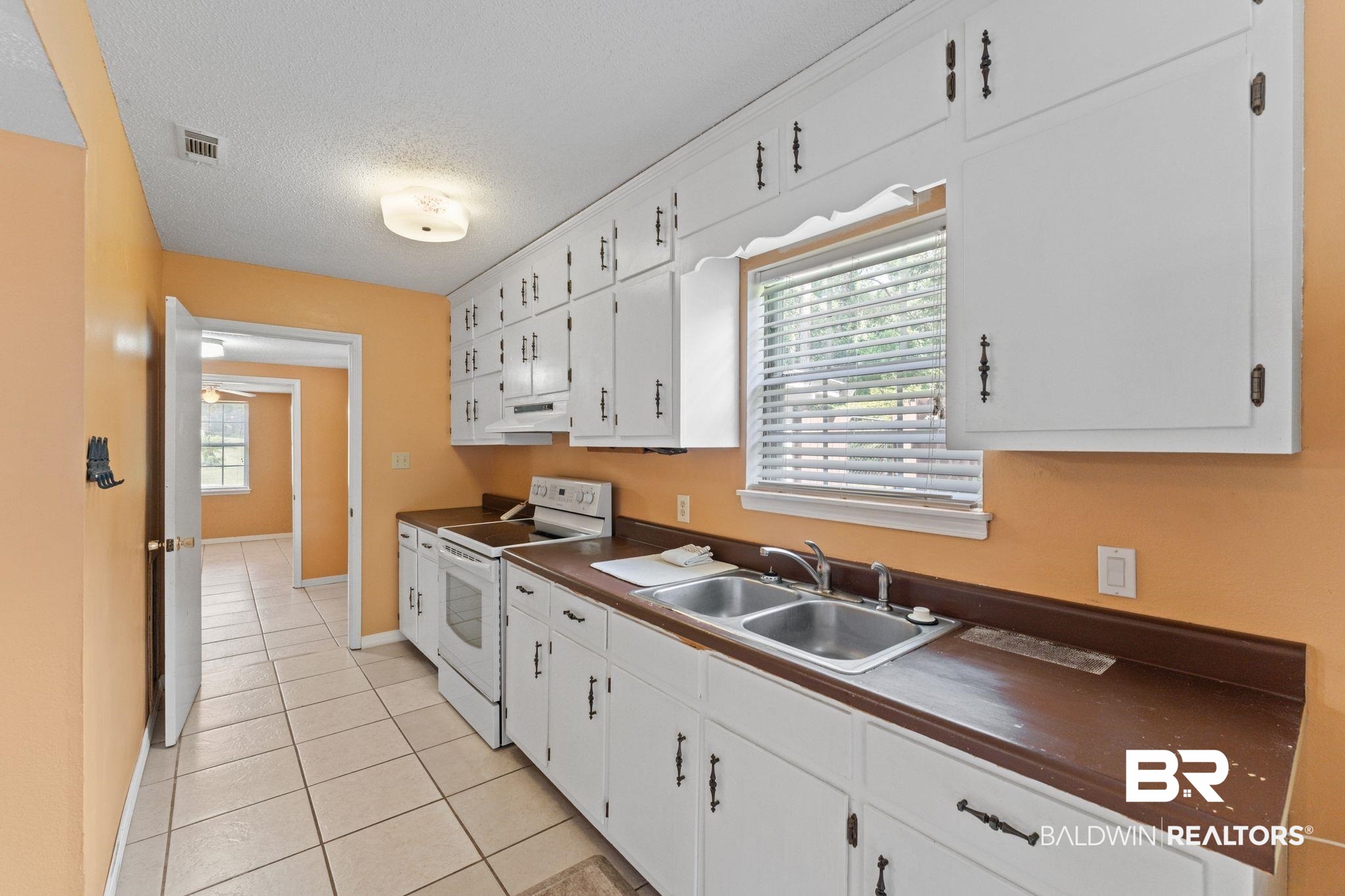 14095 Riverside Drive Foley, AL 36535 - Photo 10 of 30 Kitchen featuring white range with electric cooktop, a textured ceiling, dark countertops, white cabinets, and light tile patterned flooring