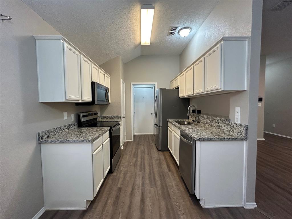 2816 Beaty Court Fort Worth, TX 76112 - Photo 6 of 24 a kitchen with stainless steel appliances granite countertop a stove top oven a sink dishwasher and a refrigerator with wooden floor